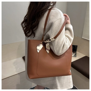 Gros plan d'un cabas en cuir marron caramel avec un foulard décoratif en soie à motifs