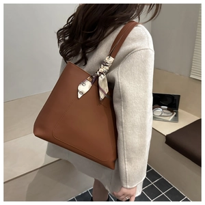 Detail view of brown faux leather tote bag with printed silk scarf and decorative stitching