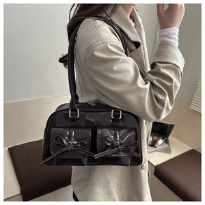 Macro shot of dark brown glossy leather bag featuring pocket detail and ribbon bow
