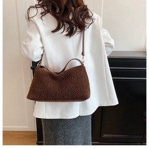 Detail view of dark brown plush bucket bag with leather strap and golden metal buckles