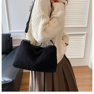 Detail of black fuzzy faux fur shoulder bag with leather strap and golden buckles
