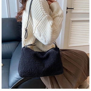 Detail of plush black faux fur shoulder bag with thin leather strap and gold buckle