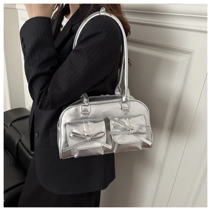 Detail of silver metallic bowling bag featuring dual bow-knot front pockets and shiny finish