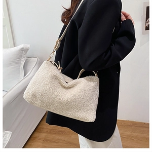 Close-up of off-white faux shearling tote bag on model showing soft texture and strap