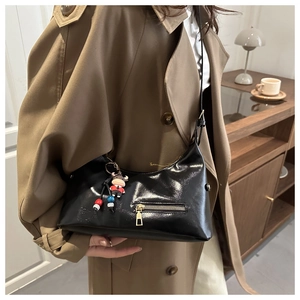 Detail of black glossy faux leather tote bag with gold zipper and cartoon bull charm