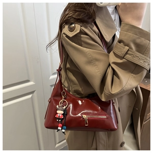 Detail of burgundy glossy faux leather shoulder bag with a cute cow-shaped pendant