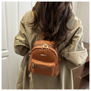 Détail d'un sac à dos marron en cuir PU tressé avec zips dorés porté par un mannequin