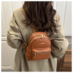 Détail d'un sac à dos marron en similicuir avec texture tressée et fermetures dorées