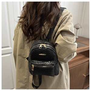 Macro detail of the black woven texture and gold zipper hardware on this mini backpack