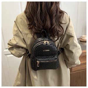Détail de la texture tressée noire sur mini sac à dos avec des fermetures éclair dorées