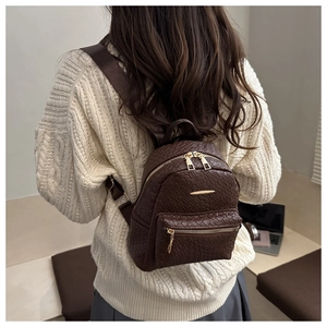 Mini brown woven leather backpack with gold zipper detail shown on a model's back
