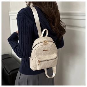 Close-up of beige woven PU leather mini backpack with gold zipper on a model back