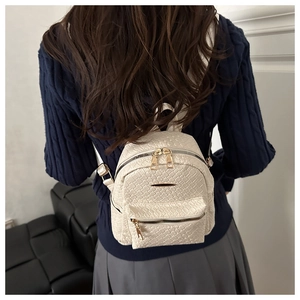 Detailed back view of model wearing a woven cream white mini backpack with gold zippers