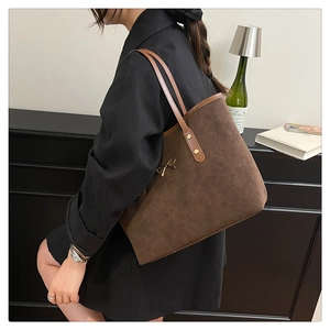 Detailed close-up of dark brown suede tote bag with elegant gold metal bow decoration