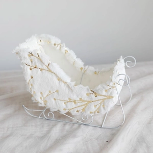 White plush Christmas sleigh decoration with elegant gold leaf patterns and metal runners