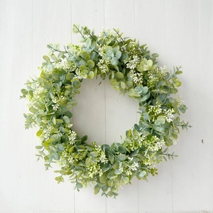 Flat lay of artificial eucalyptus wreath with white berries on white wood background
