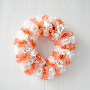 Detail of white and orange artificial tulip wreath on white wooden background