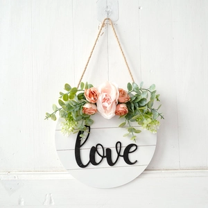 Detail of wooden love sign with artificial pink roses and green eucalyptus leaves