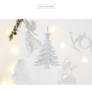 Detail of silver glitter Christmas ornaments featuring an angel and tree with bokeh lights