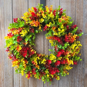 Autumn artificial wreath with gradient yellow and red leaves on rustic wood background