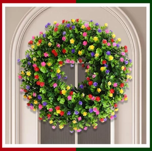 Vue détaillée de la couronne d'eucalyptus artificielle aux fleurs colorées sur une porte