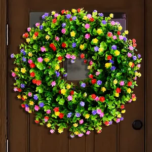 Détail d'une couronne d'eucalyptus artificielle avec des fleurs sauvages colorées