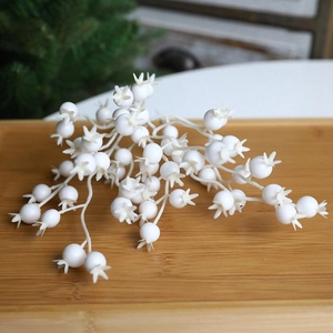 Künstliche weiße Beerenstiele für Weihnachtsbaumschmuck auf einem Holztablett