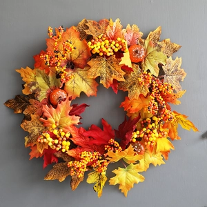 Detailed close-up of autumn wreath with maple leaves, berries and pumpkins on gray wall