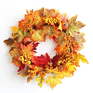 Detail of autumn wreath with maple leaves, orange berries, and small decorative pumpkins