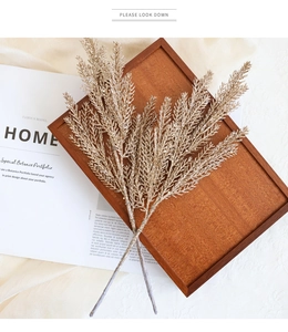Close-up of golden glitter Christmas plant stems on a satin tray for home decor
