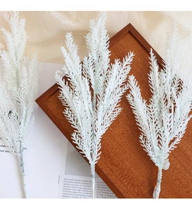 Close-up of white glittery artificial pine needles on a wooden tray for Christmas decor