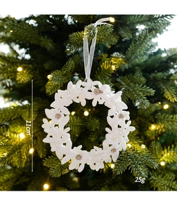 Detail van 11 cm witte acryl kerstkrans met gouden glitters op een kerstboomtak