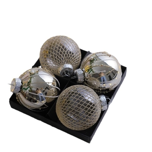 Set of four silver chrome Christmas ornaments with grid and spiral patterns in a black box