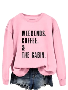 Detail of pink crewneck sweatshirt featuring WEEKENDS COFFEE & THE CABIN black text print