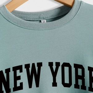 Felpa girocollo azzurra New York USA su gruccia in legno con dettagli a coste