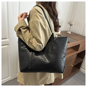 Close-up of a large black woven tote bag styled with a khaki trench coat for a chic look