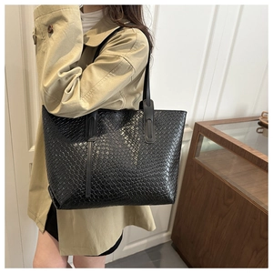 Vue latérale d'un grand sac cabas noir en cuir tressé porté à l'épaule pour femme