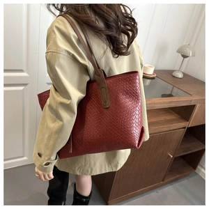 Détail d'un grand sac cabas en cuir tressé rouge brique porté à l'épaule pour femme