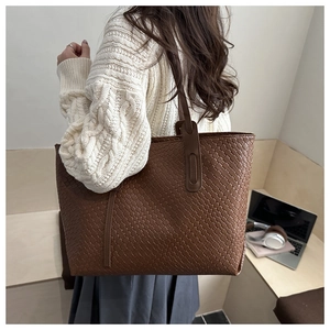Detail of a large brown woven tote bag with side fringe accents for women's daily use