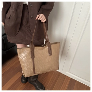 Detail of light coffee woven tote bag texture with brown leather shoulder straps