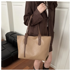 Détail d'un grand sac cabas tressé marron clair avec des anses marron foncé