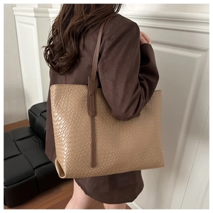 Detail of large woven tote bag in khaki showing texture and shoulder strap fit on model