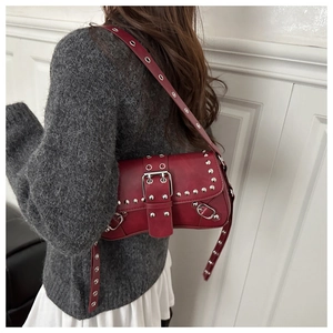 Detail of dark red punk style shoulder bag with silver studs and eyelet decorations