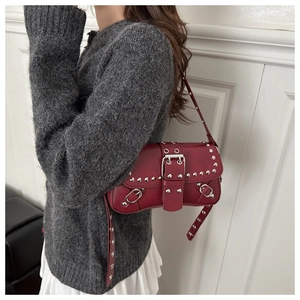 Close-up of deep red shoulder bag with silver studs and metal buckle detail