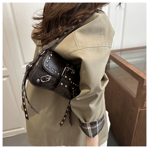 Detail of dark brown shoulder bag with silver studs and adjustable buckle strap