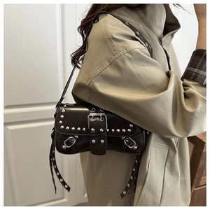 Macro detail of brown leather baguette bag featuring silver rivets and a large metal buckle