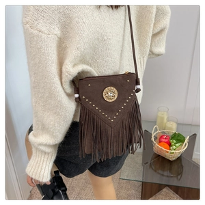 Detail view of dark brown suede crossbody bag with gold studs and long fringe tassels