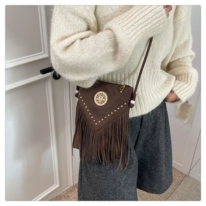 Detail of brown suede crossbody bag with fringe tassels and gold rivet decorations