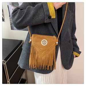 Close-up of bohemian tassel crossbody bag with suede texture and metal rivet studs