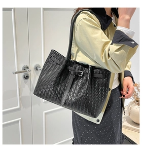 Close-up of woven texture on a black tote bag featuring a silver metal buckle detail